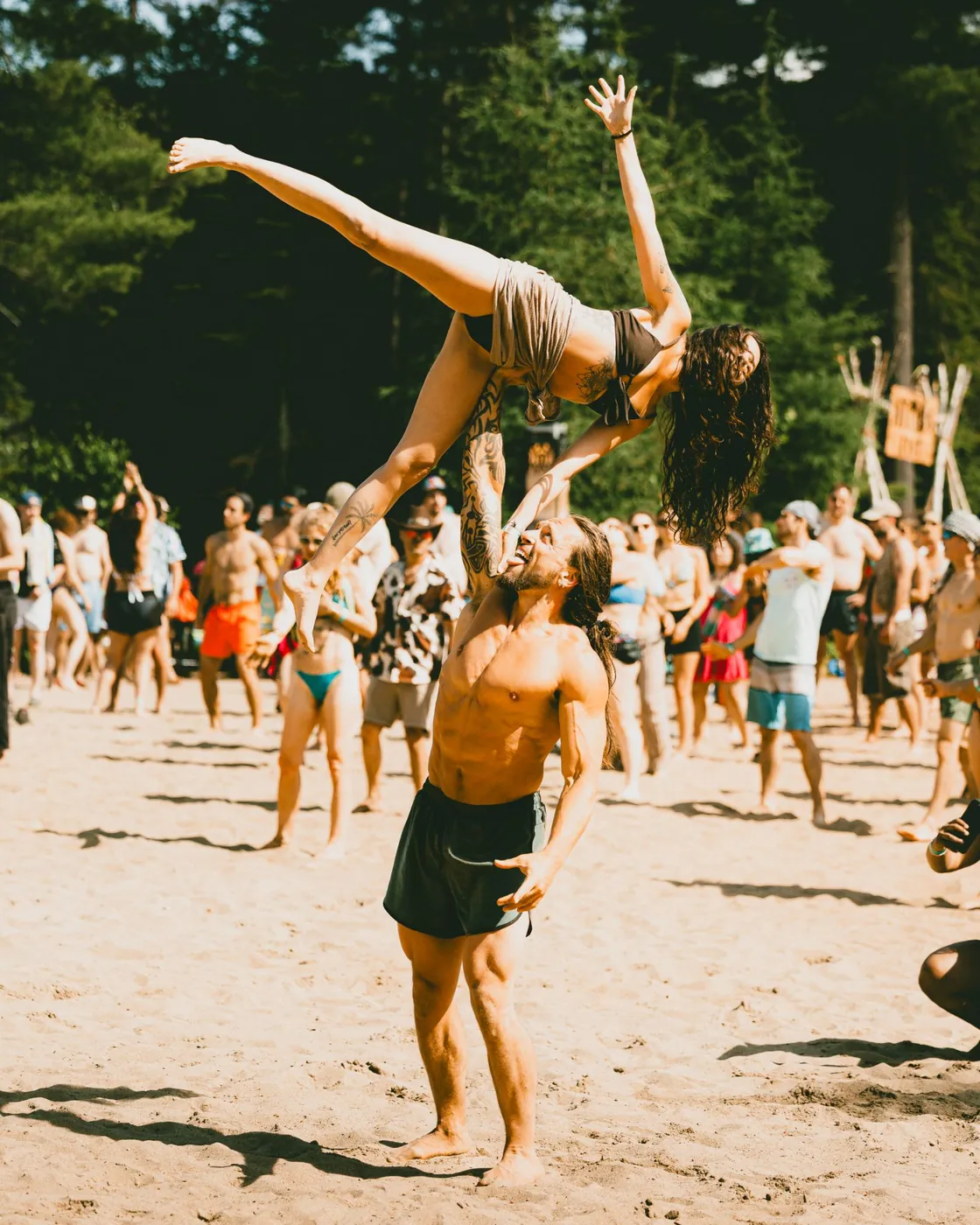 Acroyoga sur la plage : une festivalière portée à bout de bras au-dessus de la foule